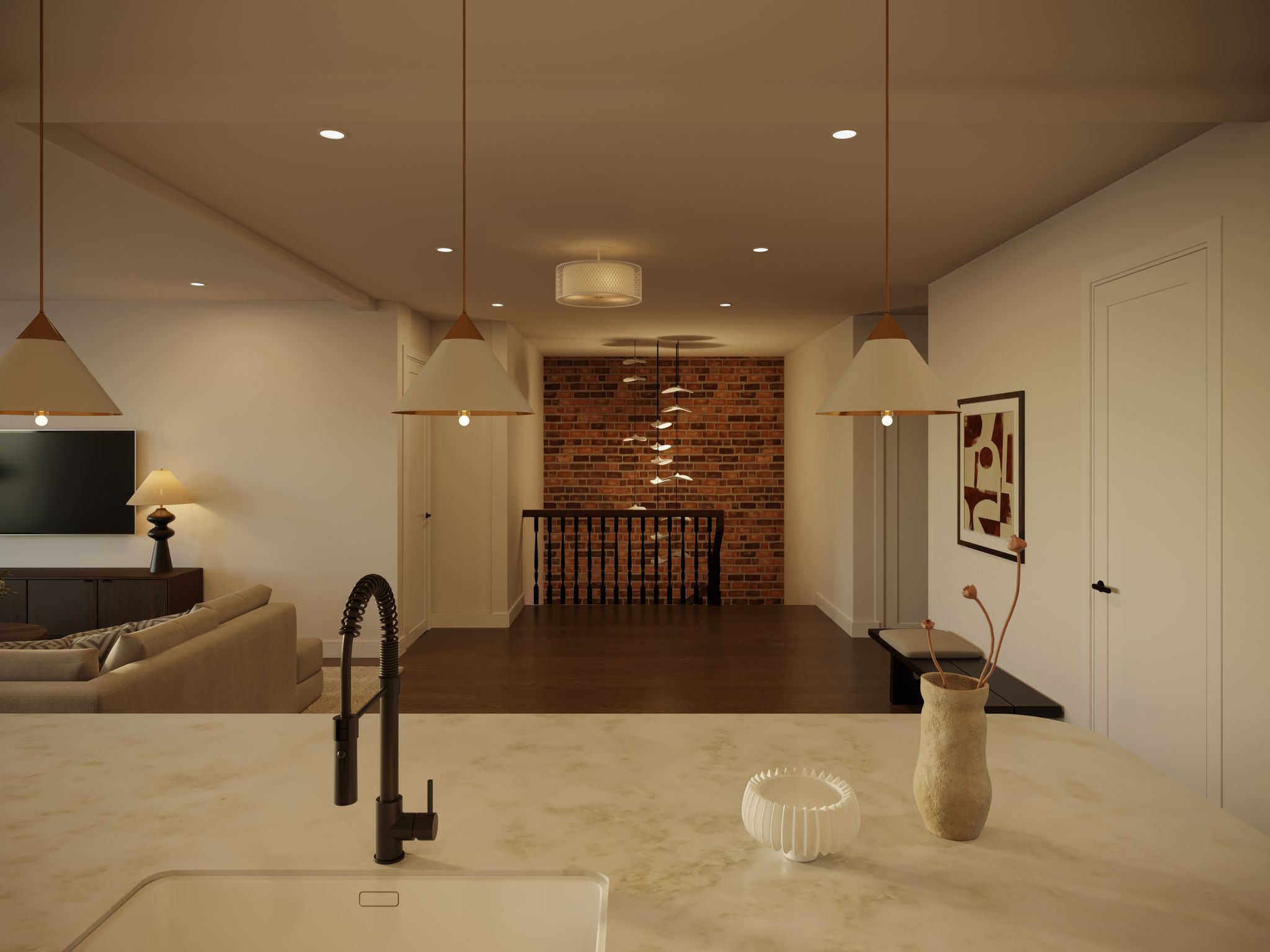 A wide interior shot of an open-plan living space featuring a kitchen island, a living room area, and a hallway leading to an exposed brick wall.